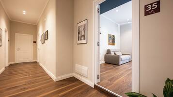 Un pasillo con suelo de madera, cuadros en las paredes y una puerta con el número 18.