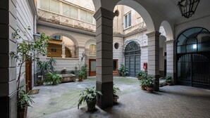 Pátio com arcos, plantas em vasos e um pilar de pedra.
