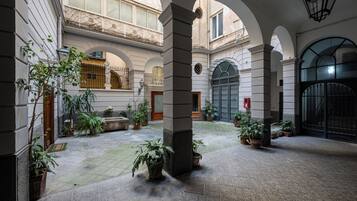 A courtyard with arches, potted plants, and a stone column.