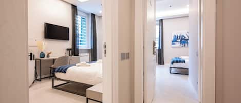 Un dormitorio moderno con cama, mesita de noche y televisor montado en la pared.
