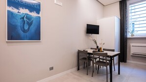 Uma sala de jantar moderna com uma mesa, cadeiras e uma TV de tela plana fixada na parede.