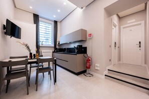 A modern kitchen with a dining area, a flat-screen TV, and a fire extinguisher. - Plebiscito Luxury Guest House (Naples)