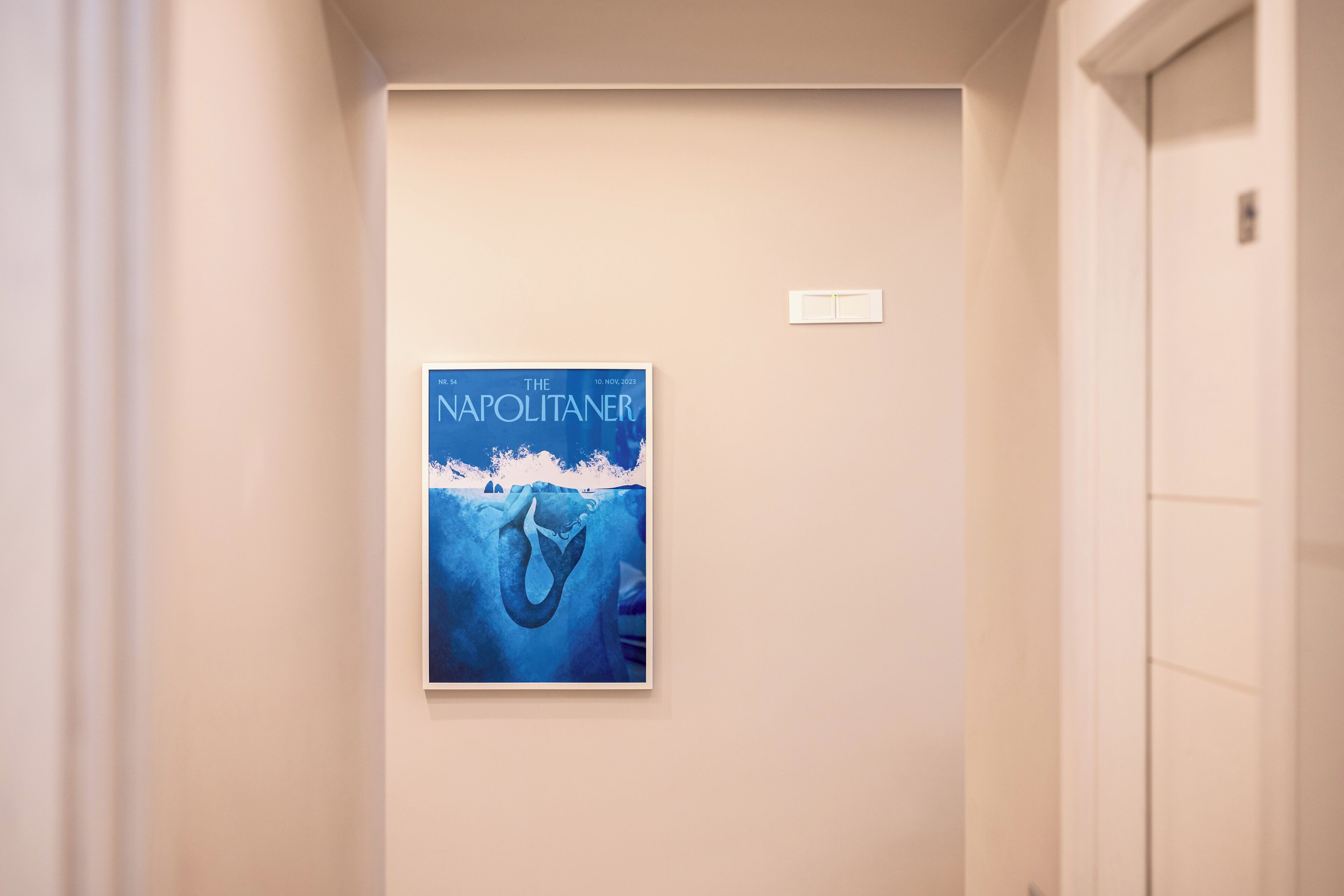 A hallway with a framed poster of 'The Napolitaner' on the wall.