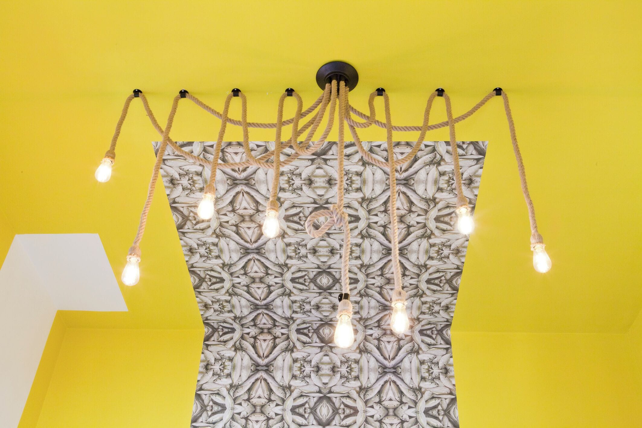 Een plafond met een patroon op de muur en een lamp met meerdere lampen.