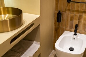 A bathroom with a white sink, a bidet, and a gold-colored basin. - Via Chiaia 123 - Camera Oltremare (Naples)