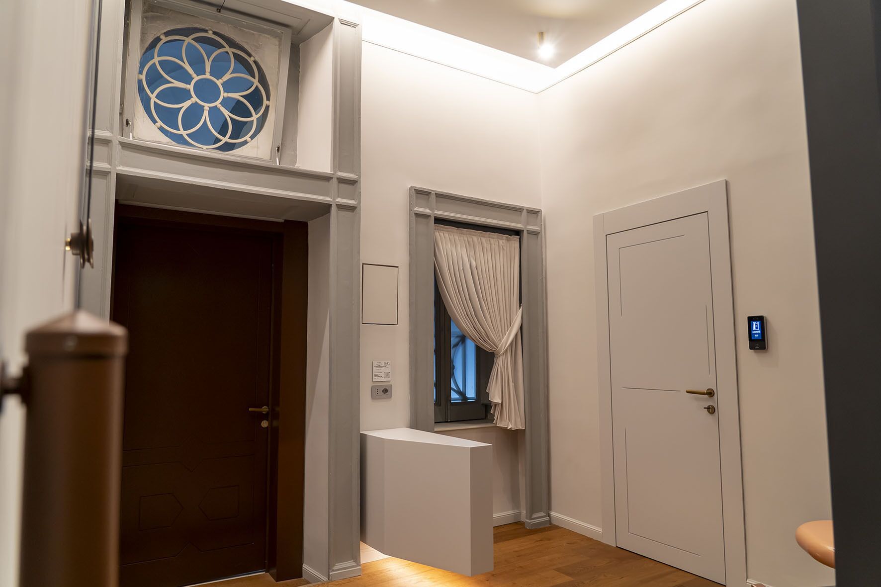 A hallway with a door, a window with a curtain, and a light fixture.