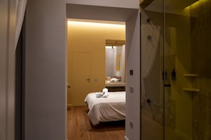A hotel room with a bed, a bedside table, a mirror, and a shower area. - Via Chiaia 123 - Camera Oltremare (Naples)