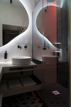 A modern bathroom with a white sink, a glass shower enclosure, and a curved wall design. - Via Chiaia 123 - Camera Oltremare (Naples)