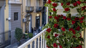 A balcony with red flowers and a view of a street with buildings. - Via Chiaia 123 - Camera Oltremare (Naples)