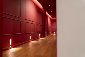 A corridor with red walls and wooden flooring, featuring recessed lighting along the walls. - Via Chiaia 123 - Camera Oltremare (Naples)
