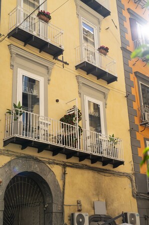 A yellow building with multiple balconies, some with flower boxes. - Via Chiaia 123 - Camera Oltremare (Naples)