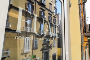 A window with the text 'FUAJE concept rooms chiaia' and a reflection of a building with balconies. - Via Chiaia 123 - Camera Oltremare (Naples)
