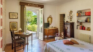 Um quarto com cama, escrivaninha, cadeira, cômoda, espelho e estante de livros.