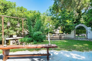 Un jardín al aire libre con un banco de madera, faroles y un arco de piedra.