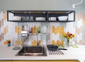 Eine moderne Küche mit einer Edelstahl-Spüle, einer schwarzen Pfanne und einer Vase mit Blumen.