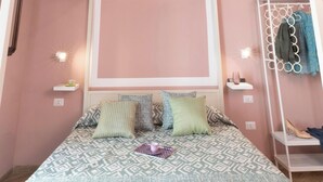 Ein Schlafzimmer mit einem Himmelbett, einer runden Kleiderstange und einem an der Wand montierten Regal.
