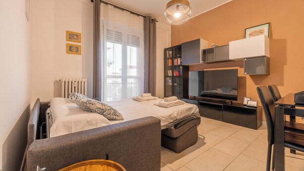 Una moderna camera d'albergo con un letto, un divano, un tavolo da pranzo e una televisione.