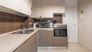 Una cucina compatta con lavello, fornello e microonde.