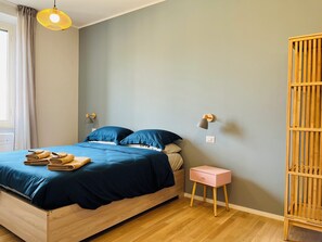 A bedroom with a bed, a nightstand, a wall-mounted lamp, and a wooden wardrobe. - Casa Duci (Rome)