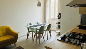 Una cocina moderna con estufa a gas, una mesa de comedor con sillas y un sofá amarillo.