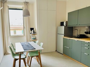 A compact kitchen with a dining table, chairs, a refrigerator, and a microwave. - Casa Duci (Rome)