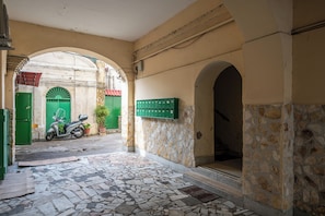 An interior courtyard with stone walls, green doors, and a scooter parked outside. - Casaré (Naples)