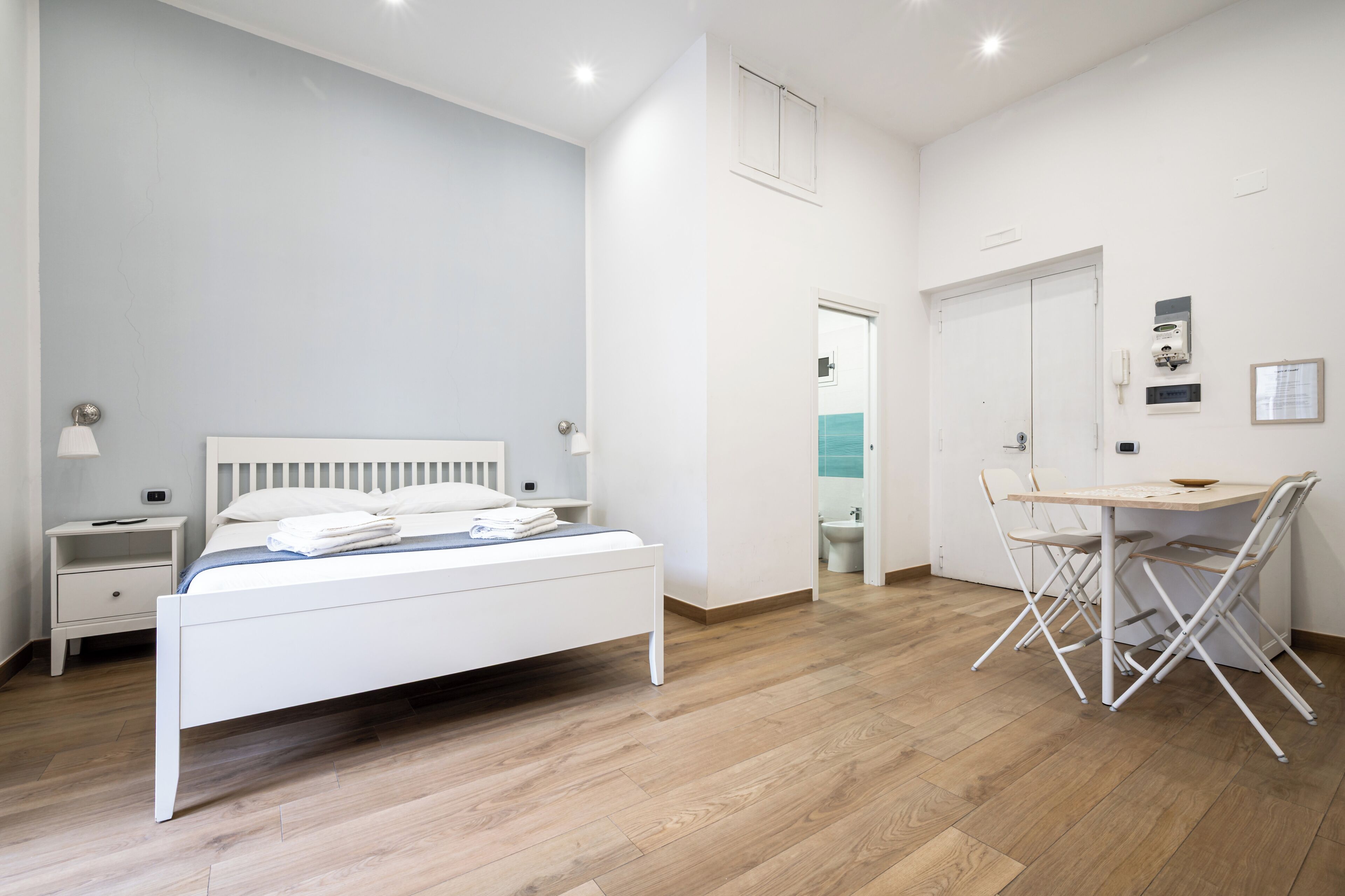 Un dormitorio con cama, mesita de noche y un escritorio con sillas.