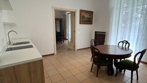 A kitchen with a sink, a dining table with chairs, and a painting on the wall. - Casa Delle Camelie (Naples)