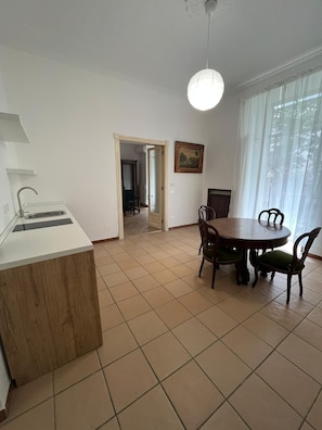 A kitchen with a sink, a dining table with chairs, and a painting on the wall. - Casa Delle Camelie (Naples)