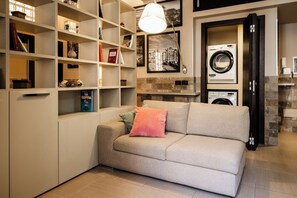 Una sala de estar moderna con un sofá, una estantería, una lavadora y una chimenea.