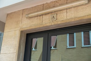 Une entrée d’immeuble avec une façade en pierre, une porte en verre et une enseigne portant la lettre « A ».