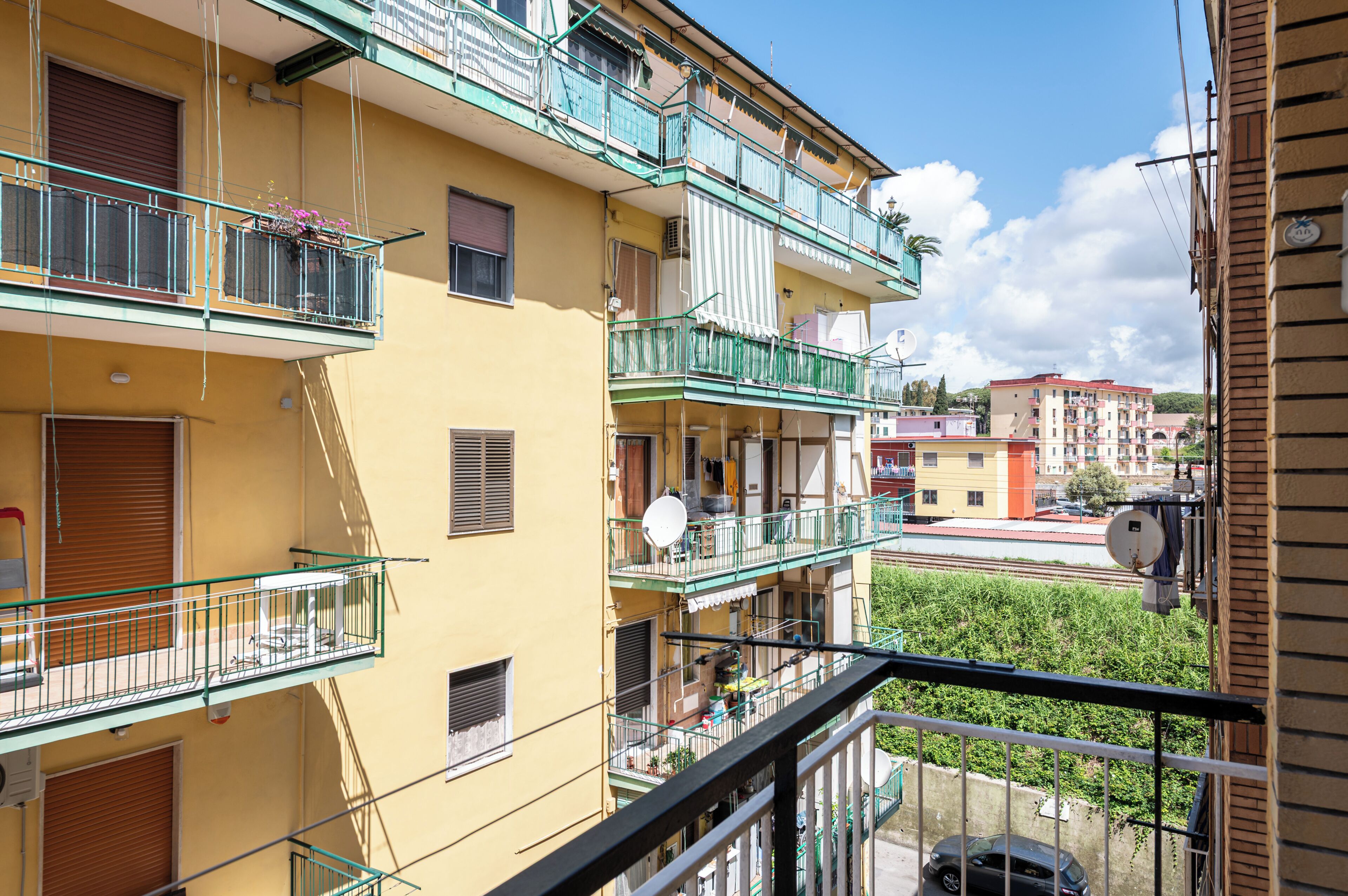 A multi-story residential building with balconies, satellite dishes, and a clear view of the street below.