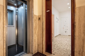 An elevator with a metallic finish, a wooden door, and a tiled floor with a speckled pattern. - Sea Breeze (Naples)