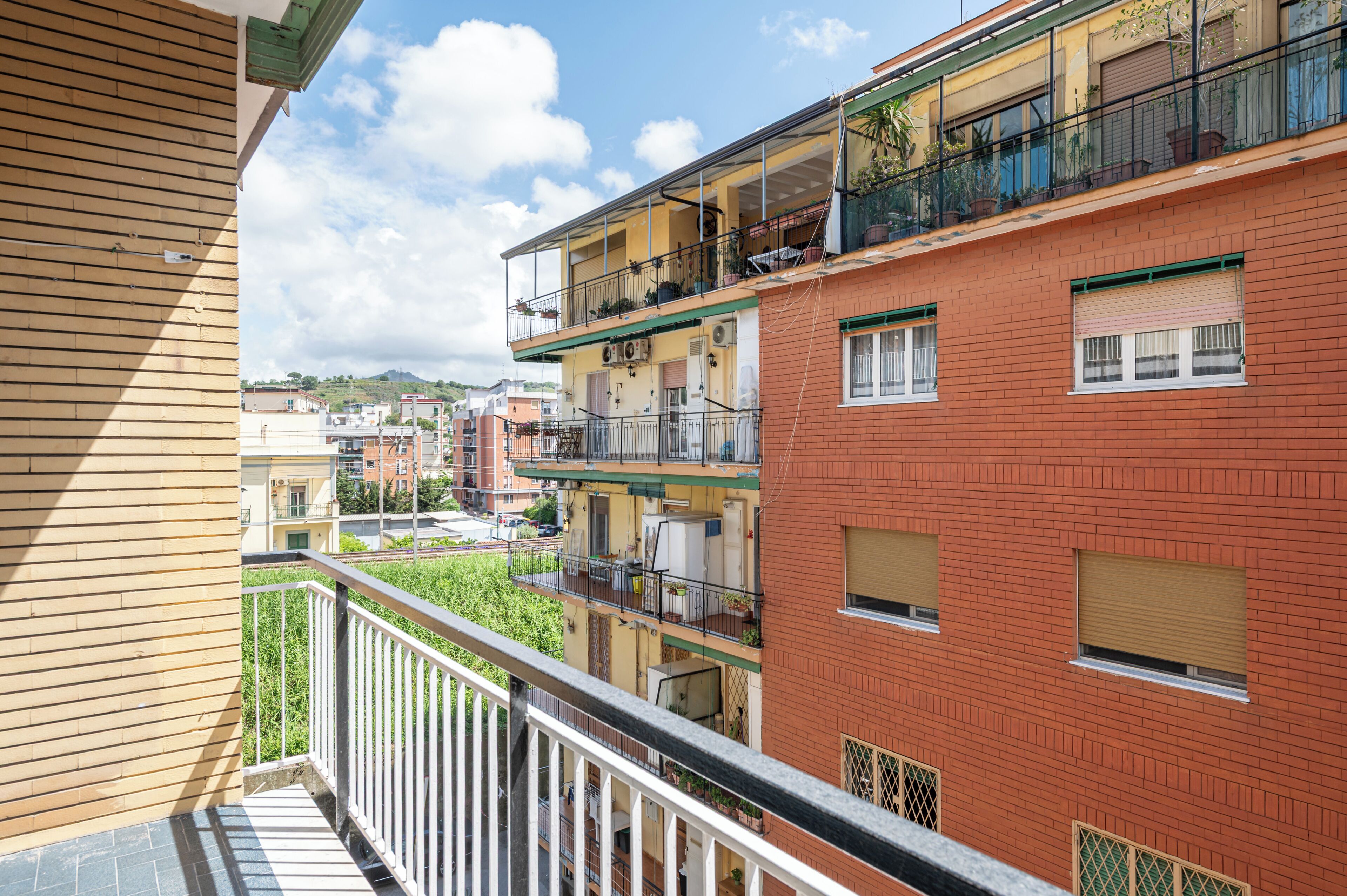 A multi-story residential building with balconies, a brick facade, and a view of the surrounding neighborhood.