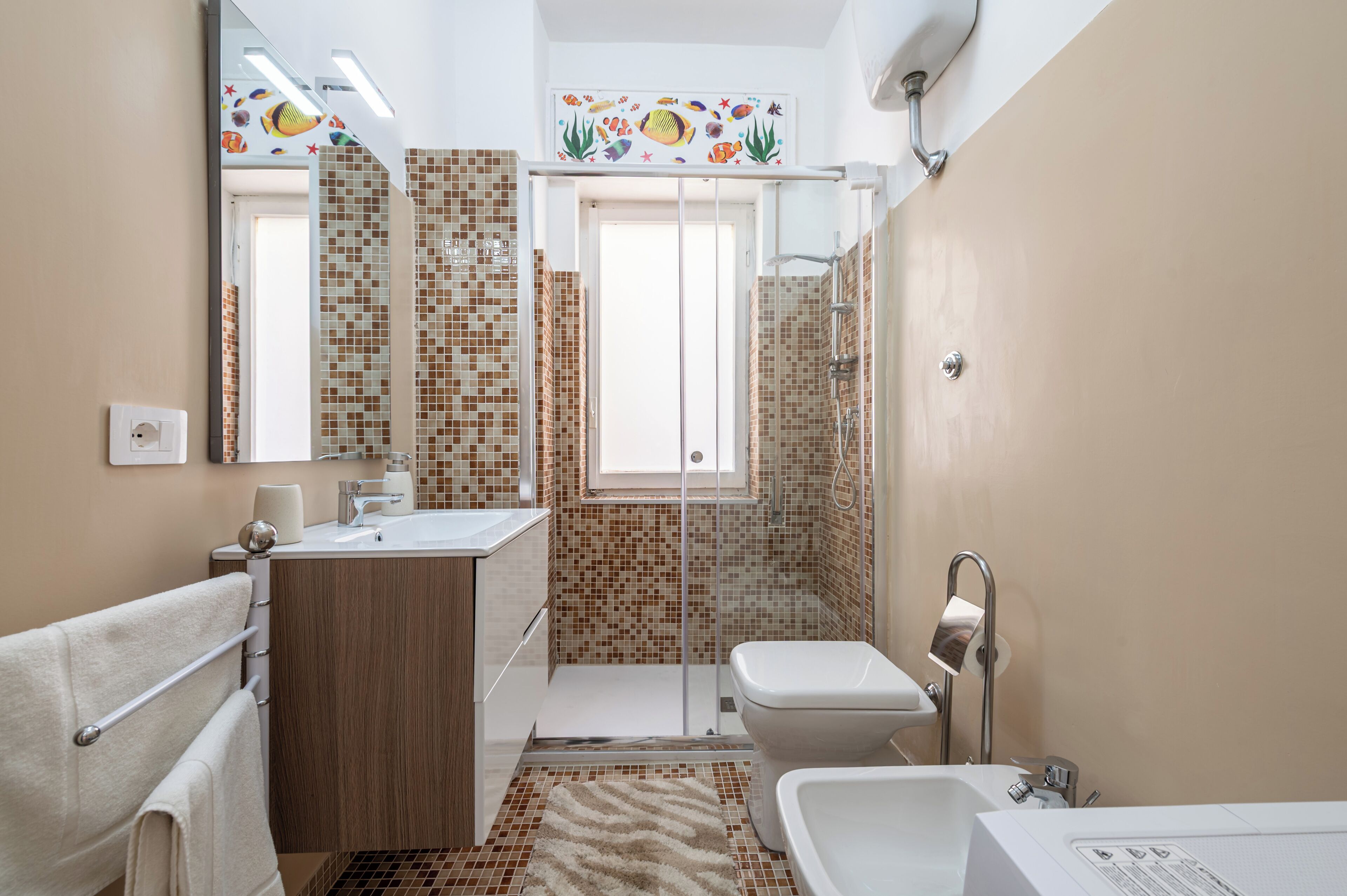 Un bagno con doccia, toilette, lavandino e specchio.