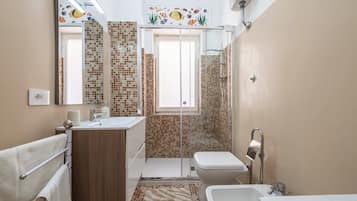 Un bagno con doccia, toilette, lavandino e specchio.