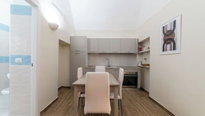 Cocina compacta con comedor, que cuenta con armarios de tonos claros, horno integrado y una pequeña encimera.