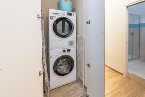 A laundry room with two stacked front-loading washing machines and a glass shower enclosure. - Villari 48 Apartment - Appartamento 1 (Naples)