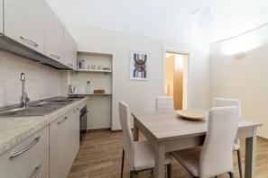 Een moderne keuken met een spoelbak, kasten en een eethoek met een tafel en stoelen.