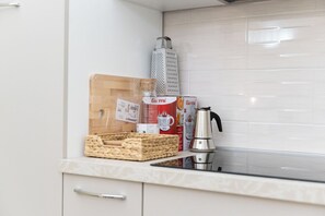 A kitchen with a wooden cutting board, a box of Gurmii yogurt, a kettle, and a grater on the counter. - Villari 48 Apartment - Appartamento 2 (Naples)