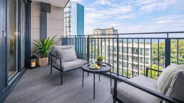 A balcony with a sofa, a small table, a potted plant, and a lantern. - Skyline Views Apartment in the Heart of Ilford (Ilford)