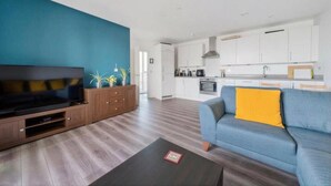 A modern living room with a flat-screen TV, a sofa, and a coffee table. - Skyline Views Apartment in the Heart of Ilford (Ilford)