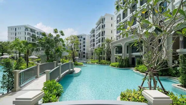 A resort with a central swimming pool, surrounded by lush greenery and white buildings with balconies. - Title Legendary by Villacarte (Choeng Thale)