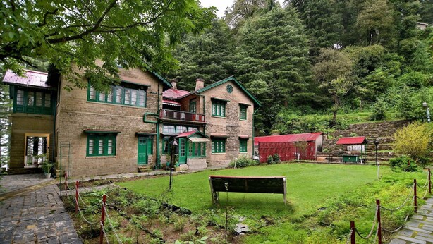 Un edificio tradicional con fachada de ladrillo, marcos de ventanas verdes y tejado rojo.