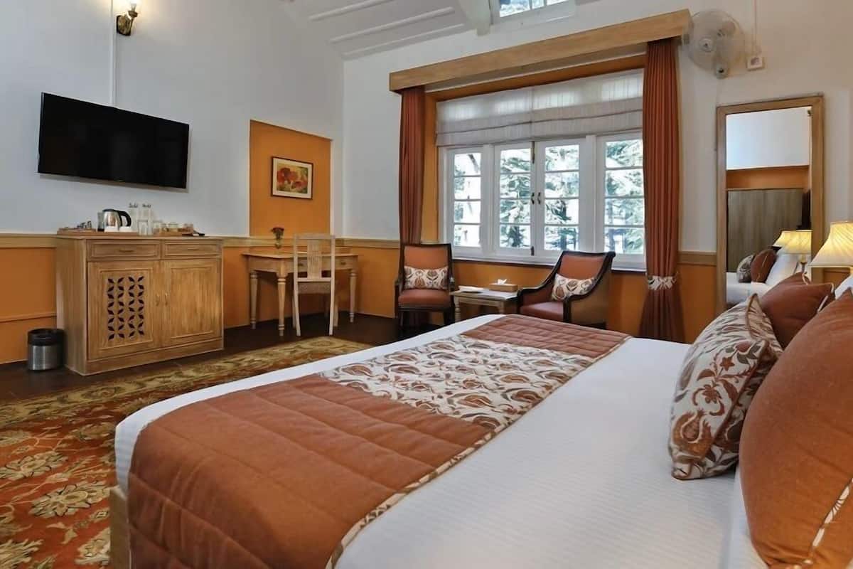 Ein Hotelzimmer mit Bett, Schreibtisch, Stuhl, Fernseher und einem fensterbepflanzten Fenster.