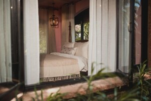 A bedroom with a bed, curtains, a hanging light fixture, and a window.