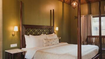 A four-poster bed with a wooden headboard, two bedside lamps, and a window with curtains.