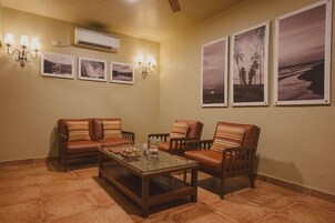 A living room with a sofa set, a coffee table, wall-mounted air conditioning, and framed pictures.