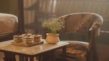 A wooden table with jars and a potted plant, a wooden chair, and a bench in a room with a window.