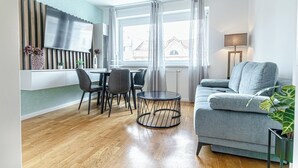 A modern living room with a grey sofa, a round coffee table, and a dining area with chairs and a table. - Chic 1BR with 1LV Apt In Central Vienna (Vienna)